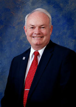 Chief Executive Officer: Warren Kean Spellman in a blue suit and red tie with tiny white polka dots.