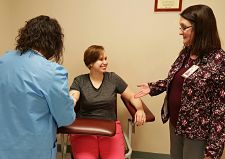 Two nurses drawing blood from a smiling patient.